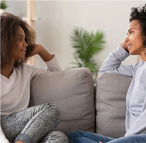 2 women facing each other while talking on the sofa